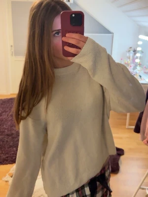 Vit stickad tröja från H&M - En stilren vit stickad tröja från H&M med rund halsringning och långa ärmar. Tröjan har en avslappnad passform och ribbstickade muddar vid hals, ärmslut och nederkant. Perfekt för lager-på-lager och enkel att matcha med olika outfits. (Den är nopprig)