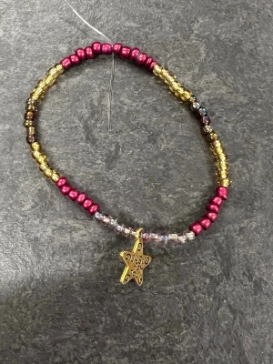Färgglatt pärlarmband med stjärnberlock Storlek M  - Ett handgjort armband. Pärlorna är trädda på en elastisk tråd vilket gör det enkelt att ta på och av. Perfekt accessoar för att addera lite färg till din stil.