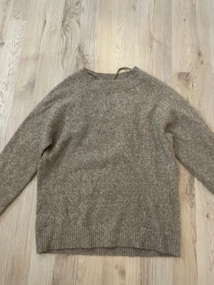 Beige stickad tröja från Vero Moda - Mysig beige stickad tröja från Vero Moda med rund halsringning och långa ärmar. Tröjan har en enkel och klassisk design med ribbstickade muddar vid hals, ärmslut och nederkant. Perfekt för lager-på-lager-stil.