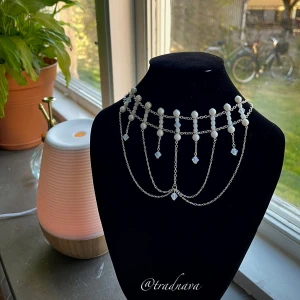 ”Elleth” - Unikt, handgjort halsband med silverpläterad kedja, vita glaspärlor och hängande glaskristaller från Preciosa. Fantasy-inspirerat som ger en känsla av Tolkiens alver🧝🏻‍♀️ I nacken sitter ett silverpläterat stavlås. Verkligen ett elegant och vackert halsband som sticker ut!☺️