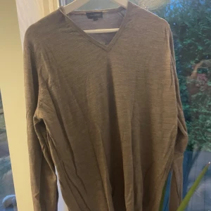 Beige v-ringad tröja John Smedley L - Snygg beige v-ringad tröja från John Smedley i storlek L. Tillverkad i tunn och mjuk merinoull, perfekt för lager-på-lager. Långärmad och klassisk passform som funkar till många olika stilar.