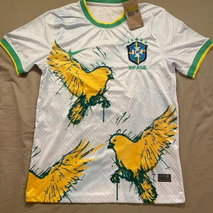 Vit Brasilien fotbollströja Nike - Brasilien fotbollströja från Nike som är vit med gröna och gula detaljer. Tröjan är storlek S, män. Den är helt ny och aldrig använd. Skickar inom 1-3 dagar