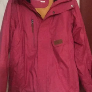 Rosa vindjacka med dragkedja - Snygg rosa vindjacka med huva och praktisk dragkedja framtill. Jackan har en bröstficka med läderdetalj och en extra ficka på sidan. Perfekt för dig som gillar färg och vill ha en jacka som sticker ut.