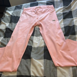 Rosa leggings från 157 i XL - Snygga ljusrosa leggings från 157 i storlek XL. De har en hög midja och är gjorda i mjukt, stretchigt syntetmaterial som sitter skönt mot kroppen. Perfekta för träning eller chill. Logga på höften.