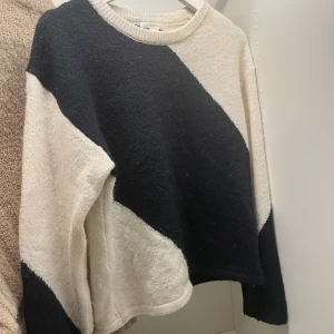 Svartvit stickad tröja med breda ränder - Snygg stickad tröja i svart och vitt med breda diagonala ränder. Tröjan har rund halsringning och långa ärmar. Perfekt för dig som gillar en stilren men ändå cool look.