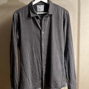 Grå skjorta från Vaillant - Säljer en stilren grå skjorta från Vaillant med klassisk krage och knäppning framtill. Skjortan har lång ärm och är tillverkad i mjuk bomull, perfekt för en clean och avslappnad look.