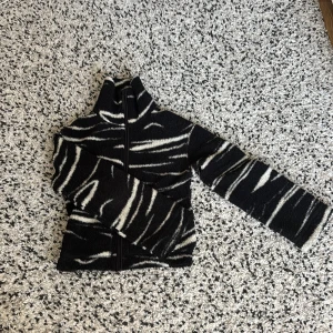 Teddyjacka  - Säljer en svart och vit fleecejacka från H&M med zebramönster. Den är knappt använd och då har kvar fluffet.