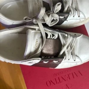 Valentino Garavani Rockstud sneakers - Snygga vita Valentino Garavani Rockstud sneakers i skinn med silverfärgad detalj och klassiska nitar på hälen. Skorna har snörning och en chunky sula. Perfekta för dig som vill ha en lyxig och trendig look.