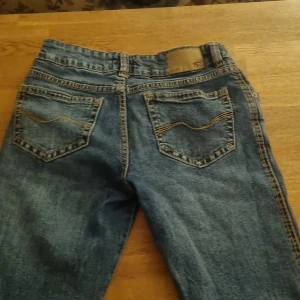 Blå bootcut jeans med dubbla knappar - Säljer ett par blå bootcut  jeans  och dubbla knappar i midjan. Klassisk femficksmodell med snygga kontrastsömmar och raka bakfickor. Jeansen har en cool, avslappnad vibe. Lager 157💕