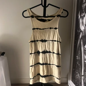 Randig ribbad linnetopp från Weekday - Säljer en beige och svart ribbad linnetopp från Weekday i storlek XS. Toppen har ett coolt randigt mönster med breda axelband och ärmlös design. Materialet är mjukt och stretchigt, perfekt för varma dagar. Passformen är normal och toppen har en avslappnad vibe.