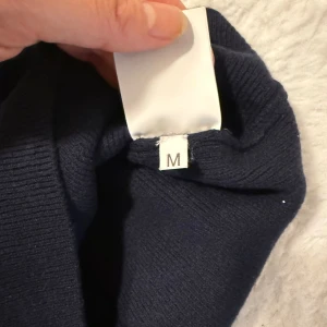 Mörkblå stickad klänning från Lauren Ralph Lauren - Supersnygg mörkblå stickad klänning från dsq med korta puffärmar och rund hals. Klänningen har en liten metallbricka med logga på bröstet och är figurnära i modellen. Perfekt för dig som gillar klassisk och stilren look.