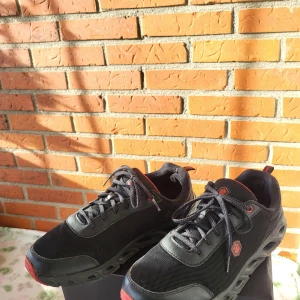 Svarta sneakers Kurtis 3FX strl 43 - Svarta sneakers från Kurtis i storlek 43 med röda detaljer och cool sula. Skorna har snörning, mesh- och syntetmaterial samt röd logga på sidan och plös. Perfekta för dig som gillar sportig och modern stil.