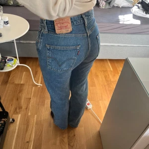 Levi's 501 blå jeans straight fit - Klassiska blå Levi's 501 jeans med rak passform och medelhög midja. Jeansen har knappgylf. Tillverkade i slitstarkt denim av bomull. Perfekta för dig som gillar en tidlös och avslappnad look. Har andvändigts mycket men inga defekter syns, de är extremt tåliga. Jeansen är enkla och går att styla till nästan allting! 