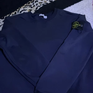 Mörkblå Stone Island sweatshirt - Säljer en mörkblå sweatshirt från Stone Island med klassisk patch på ärmen. Tröjan har rund halsringning och långa ärmar. Tillverkad i mjuk bomull för en skön känsla och stilren look.