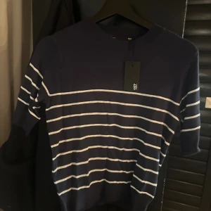 Stickad randig blå tröja  - Mörkblå stickad tröja från lager 157 i storlek XS med vita ränder. Aldrig använd enbart testad, så i nyskick (prislapp kvar).  Väldigt skön tröja.