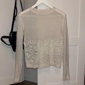 spets tröja - Superfin beige stickad tröja från Zara med lång ärm och bred spetsdetalj över magen. Tröjan har rund halsringning och är i mjukt material som känns skönt mot huden. Perfekt för dig som gillar romantiska detaljer och en stilren look.