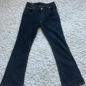 Mörkblå bootcut jeans - Snygga mörkblå jeans från BooSley med klassisk bootcut-modell. Storleken framkommer ej så jag skulle ana mellan S-M. Mått: Midja-ca 36.5cm Innerbenet -ca 72.5cm Ytterben-ca 100cm