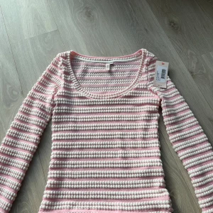 Rosa och vit randig topp från Nelly - Supersöt långärmad topp från Nelly i storlek XS. Den har ett randigt mönster i ljusrosa och vitt med en unik stickad struktur. Rundad halsringning och mjukt material som känns skönt mot huden. Perfekt för dig som gillar pastell och vill ha en chill men ändå stylish look. Helt ny kostar 350kr ny mitt pris 220kr