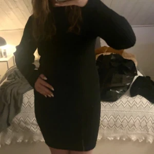 Svart ribbad stickad klänning JDY - Svart stickad klänning från JDY i storlek M. Modellen är kort, har lång ärm och är ribbstickad för en snygg och tight passform. Perfekt för dig som gillar en enkel men stilren look. Hög hals och mjukt material som känns skönt mot huden.