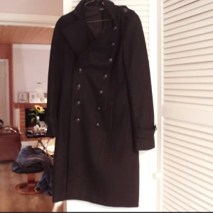 Svart lång kappa med dubbla knapprader, La Redoute stl 38,ullkappa,rock,goth - Snygg kappa i lång modell,fransk stl 38 så ngt mindre i storlek 60% ull 30% polyester 10%övriga fibrer. Mkt fint skick.Älskar min kappa,men tyvärr förliten..... Lagom varm för höst och milda vintrar. Lite mått mätt från sida till sida : överarm ca 17 cm,byst ca 44 cm,under fickorna ca 52 cm.