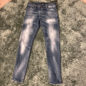 Jack&Jones jeans - Snygga blå jeans med skinny passform och slitna detaljer på både fram- och baksida. Jeansen har klassisk femficksdesign, ljusa tvättade partier och smal siluett. Perfekta för en trendig och avslappnad look.