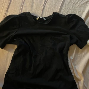 Svart topp från Pernilla Wahlgren S - Svart topp från Pernilla Wahlgren i storlek S. Modellen har puffiga korta ärmar och rund halsringning. Materialet är mjukt och känns som bomull, perfekt för en chill och stilren look. Enkel design utan mönster eller detaljer.
