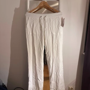 Vita linnebyxor från Nelly, low waist - Snygga vita linnebyxor från Nelly med låg midja ochs raka ben. Byxorna har resår och snörning i midjan för en skön passform, med dubbellager i byxan. Helt oanvända med prislapp på.