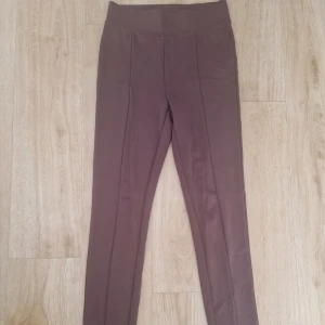 Bruna leggings från Amisu XS - Snygga bruna leggings från Amisu i storlek XS. De har hög midja och är gjorda i mjukt bomullsmaterial med stretch. Söm längs benen ger en stilren look. Perfekta för en chill och avslappnad stil.