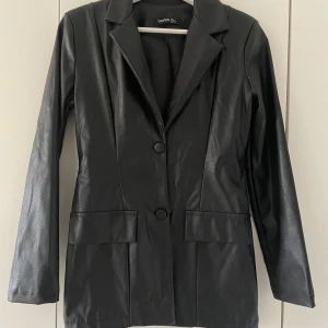 Svart skinnkavaj  - Snygg svart kavaj i skinnimitation från Boohoo. 