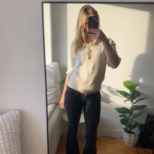 Vit stickad kofta från Holly & Whyte - Supersöt vit stickad kofta med pärlknappar och volang vid halsen från Holly & Whyte. 