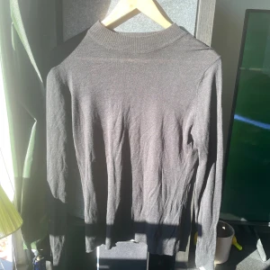 Svart stickad tröja från Indiska XS - En svart, tunnstickad tröja från Indiska i storlek XS. Tröjan har en klassisk rund hals med ribbad kant och långa ärmar. Enkel och stilren modell som passar perfekt till lager-på-lager under höst och vinter.