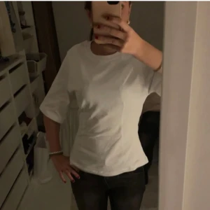 Vit kortärmad t-shirt med figursydd passform - Säljer en stilren vit t-shirt med korta ärmar och rund hals. T-shirten har en frigursydd och något loose passform, vilket gör den enkel att matcha med jeans eller shorts. Materialet känns som mjuk bomull och ger en clean look.