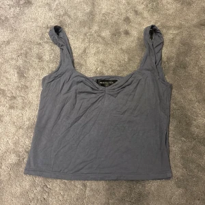 Grå/blå linnetopp från White Fox - Säljer en enkel och stilren grå/blå linnetopp från White Fox. Toppen har breda axelband, lätt v-ringad hals och en liten slits i sidan. Bra för att matcha med jeans eller kjol för en avslappnad look.