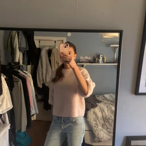 Ljusrosa stickad tröja med trekvartsärm - Supermysig ljusrosa stickad tröja med trekvartsärmar och rund hals. Tröjan har en loose passform och är lite croppad, vilket gör den perfekt till höga jeans. Materialet är mjukt och fluffigt, vilket ger en chill vibe. Perfekt för dig som gillar pastellfärger och enkel stil.