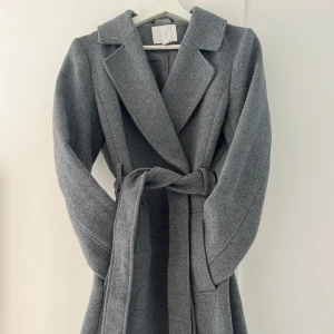 Grå kappa med bälte och knappar - Lång och varm grå kappa, knytbälte i midjan och två knappar framtill. Perfekt för dig som vill ha en stilren look under höst och vinter 🙌🏼💕