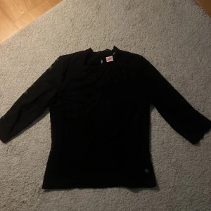 Svart spetsblus med trekvartsärm - Säljer en svart blus med spets med fina detaljer. Blusen har trekvartsärmar. Perfekt för dig som vill ha en stilren men ändå romantisk look. Använd få gånger så bra skick!