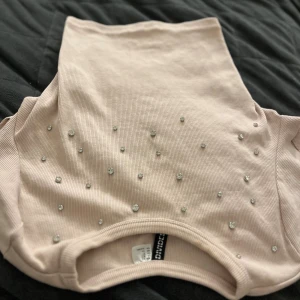 Ljusrosa croppad ribbad topp med pärlor - Supersöt ljusrosa croppad topp från h&m med ribbad struktur och glittrande pärlor framtill. Toppen är ärmlös och har en mjuk, stretchig känsla som sitter snyggt. Perfekt för dig som vill ha något extra till din outfit! 🩷🩷🤍🤍