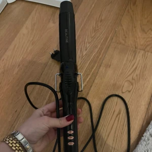 Beautine Locktång - Snygg och funktionell locktång från Beautine. Utrustad med flera värmeinställningar och lång sladd för enkel användning. Produkten ser ut att vara i gott skick utan synliga defekter eller slitage. Perfekt för att skapa vackra lockar hemma.