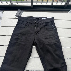 Svarta Replay jeans - Svarta jeans från Replay med klassisk femficksdesign och dragkedja. Snygg, stilren look med Slim fit och diskreta detaljer. Tillverkade i bomullsmix med stretch för extra komfort. Perfekta för dig som gillar en enkel och clean stil.