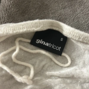 Ett vitt linne som är öppen i magen och som man kan knyta  från Gina Tricot - Ett linne/topp som är öppen i magen och som man kan knyta.