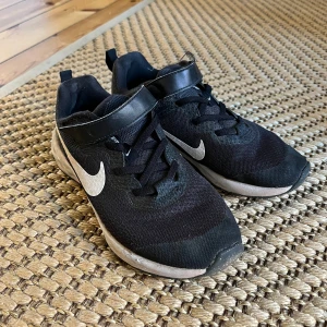 Svarta Nike sneakers med vit sula - Svarta Nike sneakers säljes. Skorna är slitna, men håller en stund till!