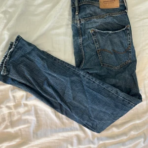 Blå jeans från Jack & Jones - Säljer ett par klassiska blå jeans från Jack & Jones med raka ben och snygga kontrastsömmar. Jeansen har två bakfickor och en tydlig logopatch bak i midjan. Materialet är slitstarkt denim och färgen är mörkblå med lätt tvättad look.  Pris kan diskuterar vid snabb affär 