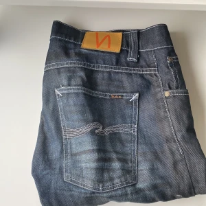 Nudie Jeans Straight Svea blå 33/36 - Snygga blå jeans från Nudie Jeans, modell Straight Svea. Klassisk femficksdesign med kontrastsömmar och coolt broderi på bakfickan. Tillverkade i 100% bomull för skön känsla och bra passform. Perfekt för dig som gillar stilrena och raka jeans.med riktigt feta slitningar kom med bud!!!!!
