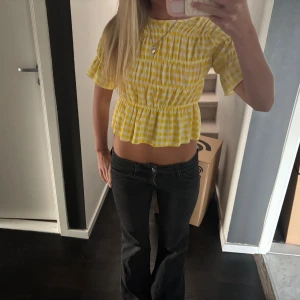 Gul rutig blus med volang - Säljer en söt gul och vit rutig blus med korta ärmar och volang nedtill.