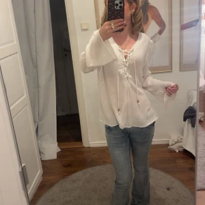 Vit blus med snörning och vida ärmar - Säljer en vit blus med snygg snörning framtill och vida ärmar. Säljer pga för stor, men skit snygg o passar till allt!