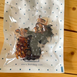 Mix av små hårklämmor  - Säljer ett set med små hårklämmor i olika färger och former. Innehåller svarta, bruna, rosa och röda klämmor, vissa med glittrig finish. Perfekta för att skapa snygga frisyrer eller sätta upp hårslingor! Kan köpas styckvis men då måste man köpa minst 4 stycken. 2kr/st, alla för 15