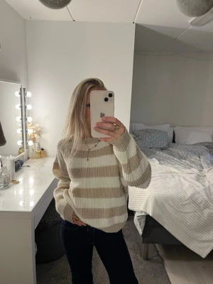 Beige och vit randig stickad tröja - Supermysig stickad tröja med breda beige och vita ränder. Tröjan har en relaxed fit med långa ärmar och rund halsringning. Perfekt för lager-på-lager och chill dagar.