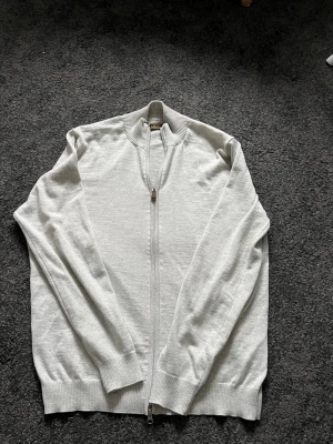 Ljusgrå helzip från Stenströms - Säljer en stilren ljusgrå helzip från Stenströms i storlek XL (sitter dock som Large). Koftan har hel dragkedja framtill, ribbade muddar och krage. Tillverkad i mjukt material som känns skönt mot huden. Perfekt till lager på lager och enkel att matcha. Hör av dig vid frågor!👍