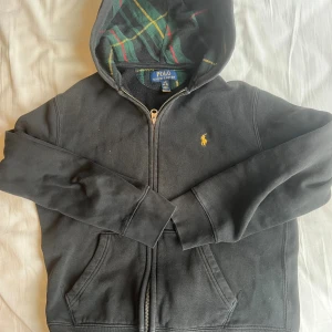 Ralph lauren zip hoodie - Väldigt unik och ovanlig Ralph lauren zip up med burberry liknande mönster i luvan. Tyvärr så har den blivit för liten för mig. Passar någon som är 155-165 cm lång ungefär. Det står L 14-16 men jag tycker den är mindre än de flesta andra som har den storleken.