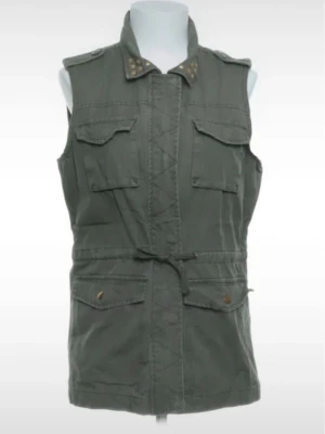 Grön utilityväst med knyt och nitar - Snygg grön utilityväst med fyra stora fickor framtill, knyt i midjan och coola nitar på kragen. Västen har axelklaffar och stängs med dold dragkedja. Perfekt för dig som gillar en avslappnad men edgy stil.